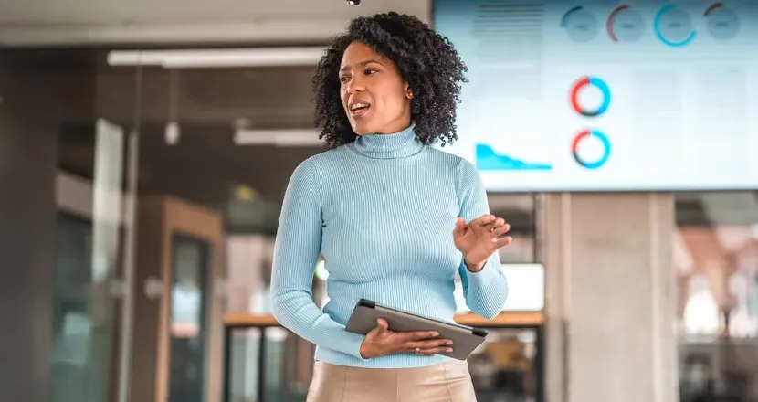 A confident business professional presents data during a meeting, demonstrating leadership and analytical skills gained through an MBA.