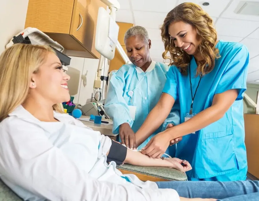 Nursing student learning how to draw blood in lab simulation with nurse teacher